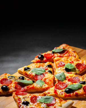 Mozzarella peyniri, salam, zeytin, biber, Baharat ve Taze ıspanak ile Pepperoni Pizza. Koyu gri siyah arduvaz arka plan üzerinde İtalyan pizza