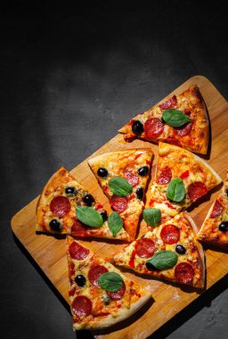 Mozzarella peyniri, salam, zeytin, biber, Baharat ve Taze ıspanak ile Pepperoni Pizza. Koyu gri siyah arduvaz arka plan üzerinde İtalyan pizza