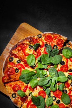 Pizza Mozzarella peyniri, Domates, biber, zeytin, Baharat ve Taze ıspanak ile. İtalyan pizzası. Pizza Margherita veya Margarita Koyu gri siyah kayrak arka plan üzerinde