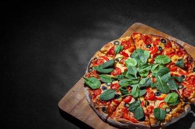 Pizza Mozzarella peyniri, Domates, biber, zeytin, Baharat ve Taze ıspanak ile. İtalyan pizzası. Pizza Margherita veya Margarita Koyu gri siyah kayrak arka plan üzerinde