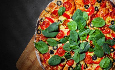 Pizza Mozzarella peyniri, Domates, biber, zeytin, Baharat ve Taze ıspanak ile. İtalyan pizzası. Pizza Margherita veya Margarita Koyu gri siyah kayrak arka plan üzerinde