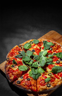 Pizza Mozzarella peyniri, Domates, biber, zeytin, Baharat ve Taze ıspanak ile. İtalyan pizzası. Pizza Margherita veya Margarita Koyu gri siyah kayrak arka plan üzerinde