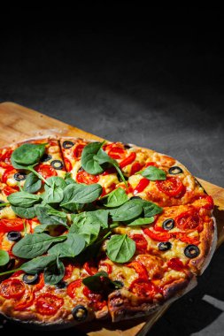 Pizza Mozzarella peyniri, Domates, biber, zeytin, Baharat ve Taze ıspanak ile. İtalyan pizzası. Pizza Margherita veya Margarita Koyu gri siyah kayrak arka plan üzerinde