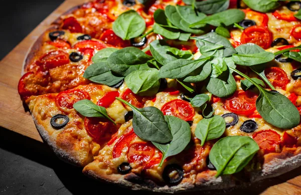 Pizza Mozzarella peyniri, Domates, biber, zeytin, Baharat ve Taze ıspanak ile. İtalyan pizzası. Pizza Margherita veya Margarita Koyu gri siyah kayrak arka plan üzerinde