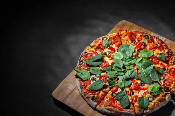 Pizza Mozzarella peyniri, Domates, biber, zeytin, Baharat ve Taze ıspanak ile. İtalyan pizzası. Pizza Margherita veya Margarita Koyu gri siyah kayrak arka plan üzerinde