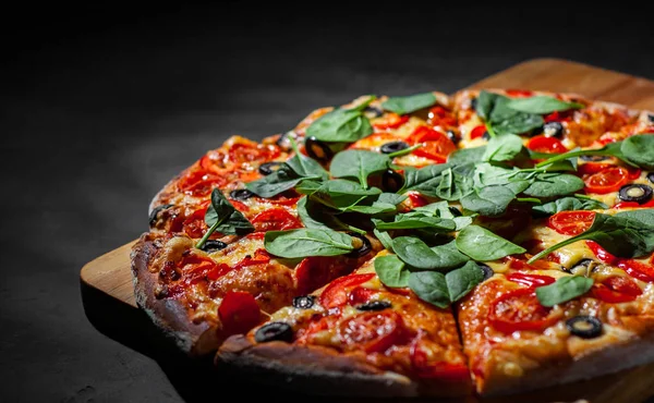 Pizza Mozzarella peyniri, Domates, biber, zeytin, Baharat ve Taze ıspanak ile. İtalyan pizzası. Pizza Margherita veya Margarita Koyu gri siyah kayrak arka plan üzerinde