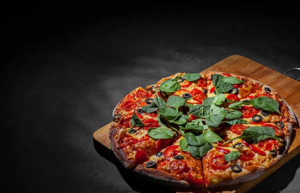 Pizza Mozzarella peyniri, Domates, biber, zeytin, Baharat ve Taze ıspanak ile. İtalyan pizzası. Pizza Margherita veya Margarita Koyu gri siyah kayrak arka plan üzerinde