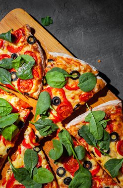 Pizza Mozzarella peyniri, Domates, biber, zeytin, Baharat ve Taze ıspanak ile. İtalyan pizzası. Pizza Margherita veya Margarita Koyu gri siyah kayrak arka plan üzerinde