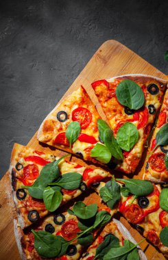 Pizza Mozzarella peyniri, Domates, biber, zeytin, Baharat ve Taze ıspanak ile. İtalyan pizzası. Pizza Margherita veya Margarita Koyu gri siyah kayrak arka plan üzerinde