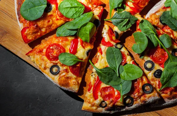 Pizza Mozzarella peyniri, Domates, biber, zeytin, Baharat ve Taze ıspanak ile. İtalyan pizzası. Pizza Margherita veya Margarita Koyu gri siyah kayrak arka plan üzerinde