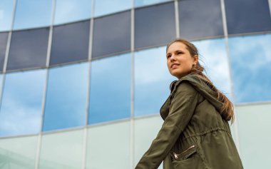 Uzun saçlı genç genç esmer kız Açık portre. Kopyalama alanı ile arka planda cam bina.