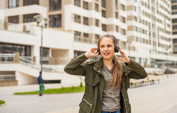 長い髪を持つ若いティーンエイジャーブルネットの女の子の屋外の肖像画 携帯電話で音楽を聴く若い女性 — ストック写真