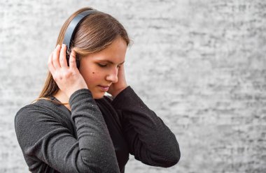 gri duvar arka plan üzerinde kablosuz kulaklık müzik dinleuzun saçlı genç genç esmer kız portresi