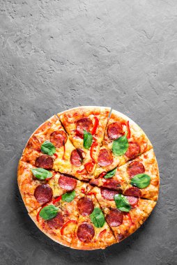 Mozzarella peynirli Pepperoni Pizza, salam, biber, baharat ve taze ıspanak. Koyu gri arka planda İtalyan pizzası