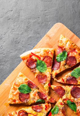 Mozzarella peynirli Pepperoni Pizza, salam, biber, baharat ve taze ıspanak. Koyu gri arka planda İtalyan pizzası