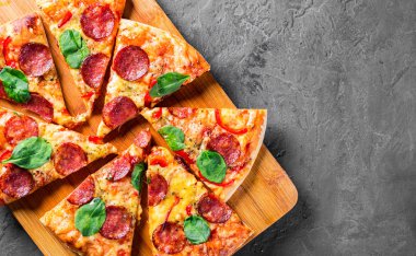 Mozzarella peynirli Pepperoni Pizza, salam, biber, baharat ve taze ıspanak. Koyu gri arka planda İtalyan pizzası