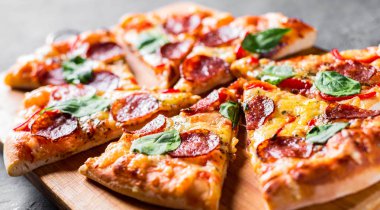 Mozzarella peynirli Pepperoni Pizza, salam, biber, baharat ve taze ıspanak. Koyu gri arka planda İtalyan pizzası