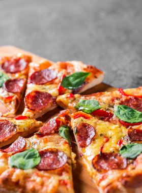 Mozzarella peynirli Pepperoni Pizza, salam, biber, baharat ve taze ıspanak. Koyu gri arka planda İtalyan pizzası