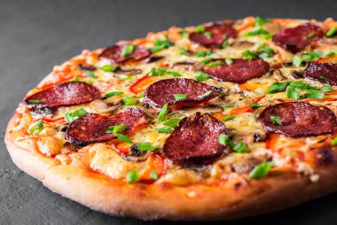 Mozzarella peyniri, salam, biber, baharat ve mantar ile Pepperoni Pizza. Koyu gri siyah arduvaz arka plan üzerinde İtalyan pizza