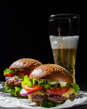 koyu siyah arka plan üzerinde et, peynir ve sebze ve bira ile iki burger
