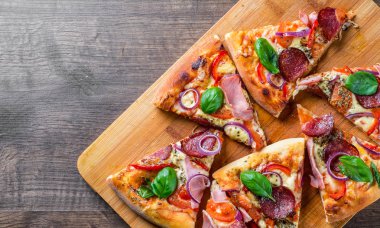 Pizza Mozzarella peynir, jambon, domates sosu, salam, soğan, biber, Baharat ve Taze fesleğen ile. Ahşap masa arka planda İtalyan pizza