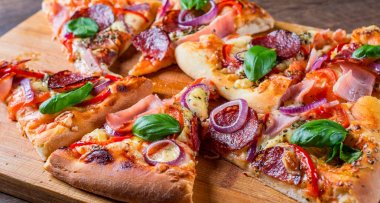 Pizza Mozzarella peynir, jambon, domates sosu, salam, soğan, biber, Baharat ve Taze fesleğen ile. Ahşap masa arka planda İtalyan pizza