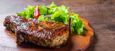 Domuz Loin pirzola ahşap masa arka plan üzerinde sebze slad ile marine et Biftek