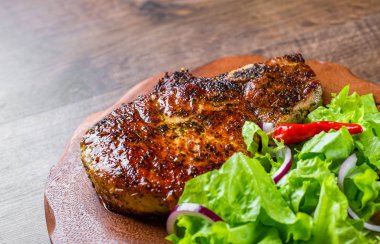 Domuz Loin pirzola ahşap masa arka plan üzerinde sebze slad ile marine et Biftek