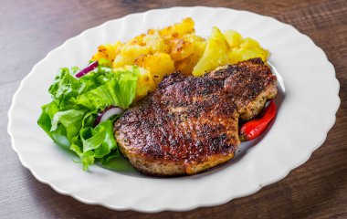 Domuz Loin pirzola ahşap masa arka plan üzerinde sebze slad ve patates ile marine et Biftek