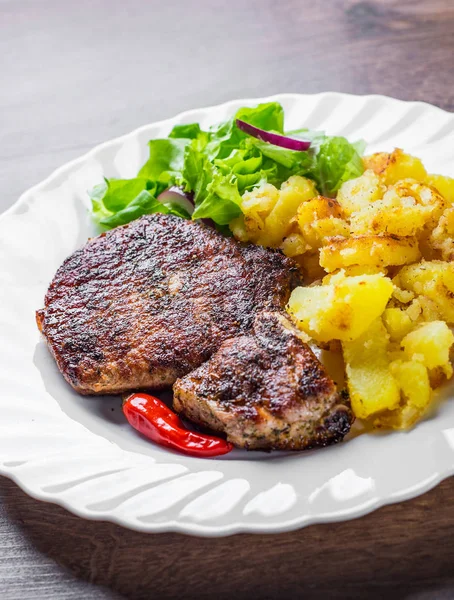 Pork Loin chops marinated meat Steak with vegetables slad and potato on wooden table background