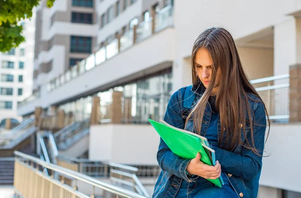 バックパックを着て本やノートブックを保持する学校の学生のティーンエイジャーの女の子に 若い十代のブルネットの少女の長い髪の屋外肖像画 街の女の子 — ストック写真