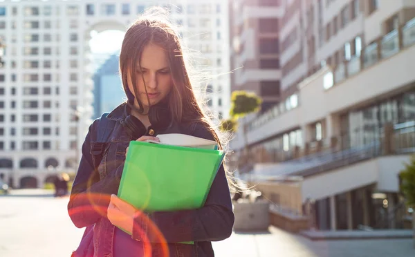 バックパックを着て本やノートブックを保持する学校の学生のティーンエイジャーの女の子に 若い十代のブルネットの少女の長い髪の屋外肖像画 街の女の子 — ストック写真