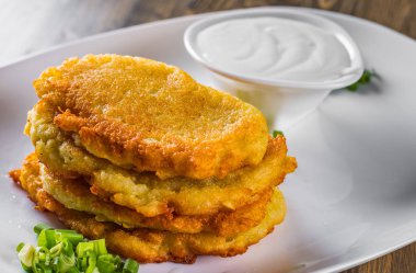 ahşap masa üzerinde bir tabakta ekşi krema ile patates krep