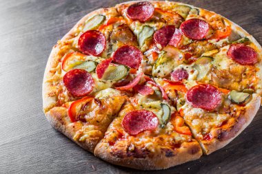 Mozzarella peyniri, salam, pastırma, Domates sosu, biber, baharat ve salatalık turşusu ile Pepperoni Pizza. Ahşap masa arka planda İtalyan pizza