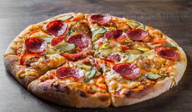 Mozzarella peyniri, salam, pastırma, Domates sosu, biber, baharat ve salatalık turşusu ile Pepperoni Pizza. Ahşap masa arka planda İtalyan pizza