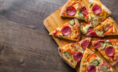 Mozzarella peyniri, salam, pastırma, Domates sosu, biber, baharat ve salatalık turşusu ile Pepperoni Pizza. Ahşap masa arka planda İtalyan pizza