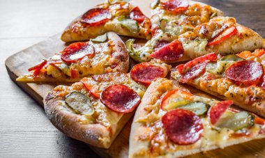 Mozzarella peyniri, salam, pastırma, Domates sosu, biber, baharat ve salatalık turşusu ile Pepperoni Pizza. Ahşap masa arka planda İtalyan pizza