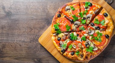 Mozzarella peyniri, Domates, biber, zeytin, mantar, Baharat ve Taze yaprak ile dilimlenmiş Pizza. Ahşap masa arka planda İtalyan pizza