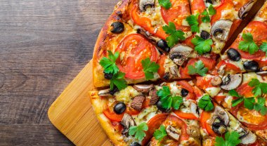 Mozzarella peyniri, Domates, biber, zeytin, mantar, Baharat ve Taze yaprak ile dilimlenmiş Pizza. Ahşap masa arka planda İtalyan pizza