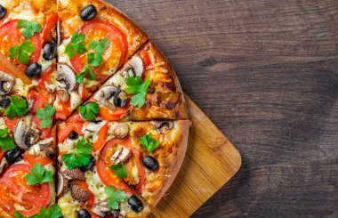 Mozzarella peyniri, Domates, biber, zeytin, mantar, Baharat ve Taze yaprak ile dilimlenmiş Pizza. Ahşap masa arka planda İtalyan pizza