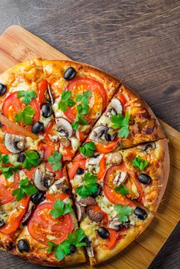 Mozzarella peyniri, Domates, biber, zeytin, mantar, Baharat ve Taze yaprak ile dilimlenmiş Pizza. Ahşap masa arka planda İtalyan pizza