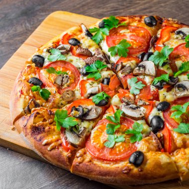 Mozzarella peyniri, Domates, biber, zeytin, mantar, Baharat ve Taze yaprak ile dilimlenmiş Pizza. Ahşap masa arka planda İtalyan pizza