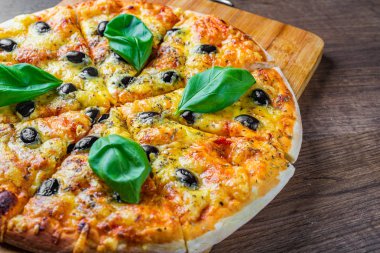 Mozzarella peynirli pizza, domates, biber, zeytin, baharat ve taze fesleğen. İtalyan pizzası. Margherita Pizzası ya da Margarita Ahşap masa arkasında