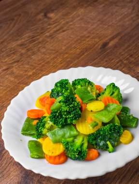 Karışık sebzeler. yeşil fasulye, brokoli ve ahşap bir masa arka plan üzerinde beyaz tabakta havuç.