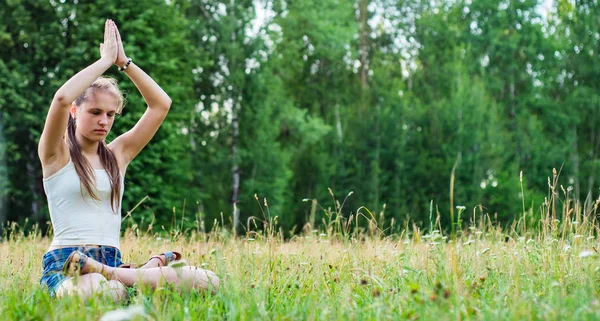 公園の草の上でヨガを練習長い髪を持つ若いティーンエイジャーブルネットの女の子 — ストック写真