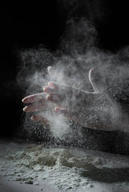 kopya alanı ile beyaz un ve siyah arka plan sıçrama ile kadın şef el alkış.