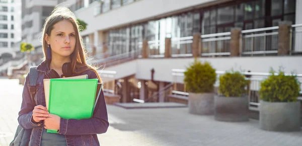 バックパックを着て本やノートブックを保持する学校の学生のティーンエイジャーの女の子に 若い十代のブルネットの少女の長い髪の屋外肖像画 街の女の子 — ストック写真