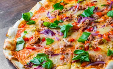 Mozzarella peyniri, soğan, ton balığı, domates sosu, biber, fesleğen ile pizza. Ahşap masada İtalyan Pizza