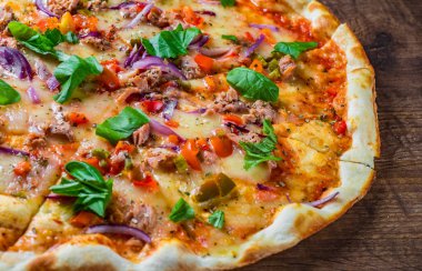 Mozzarella peyniri, soğan, ton balığı, domates sosu, biber, fesleğen ile pizza. Ahşap masada İtalyan Pizza
