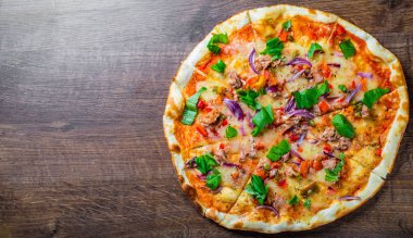 Mozzarella peyniri, soğan, ton balığı, domates sosu, biber, fesleğen ile pizza. Ahşap masada İtalyan Pizza